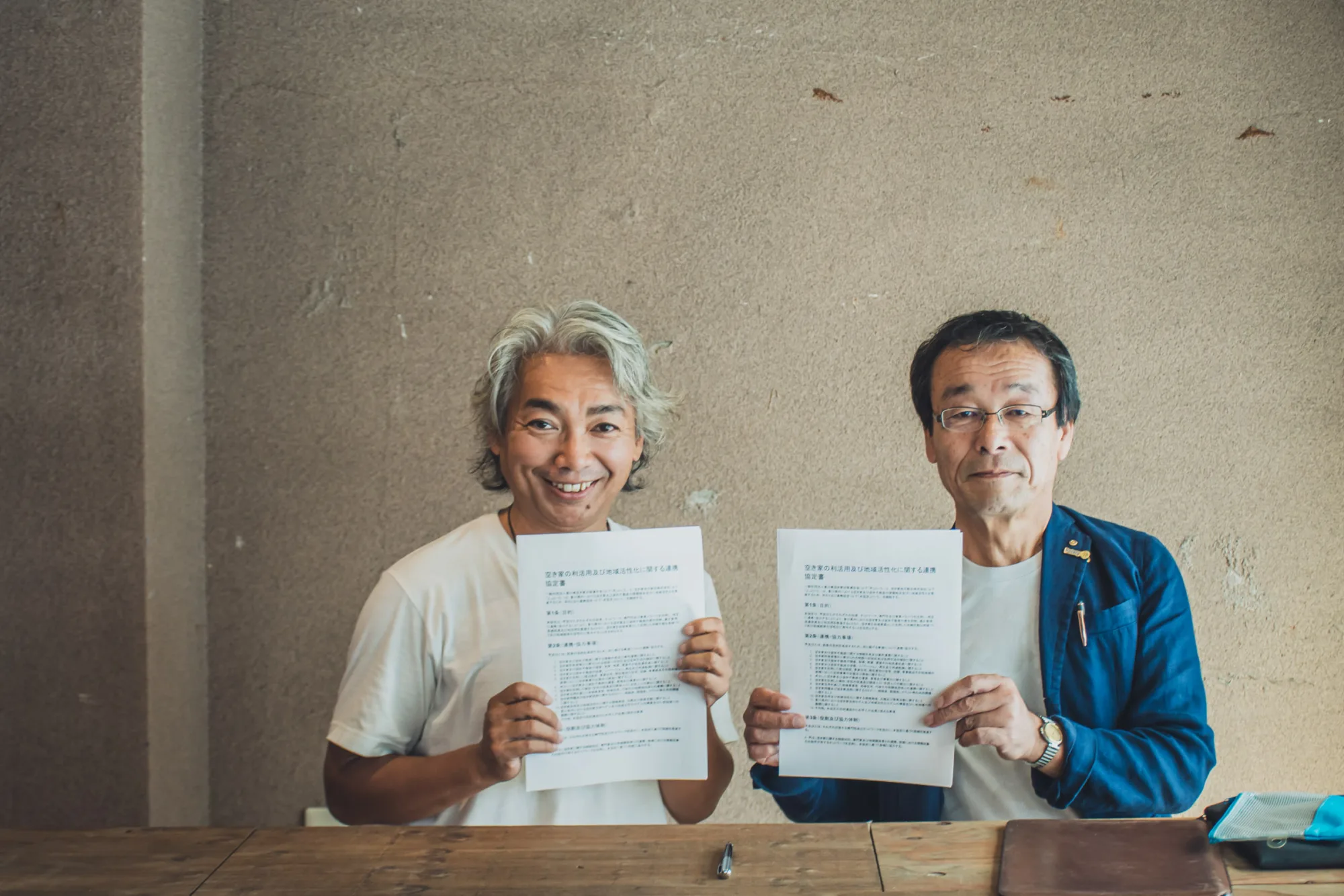 「空き家の利活用及び地域活性化に関する連携協定書」を手にする2人